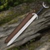 Fantasy Celtic War Sword resting on a rustic wooden log with medieval styling.